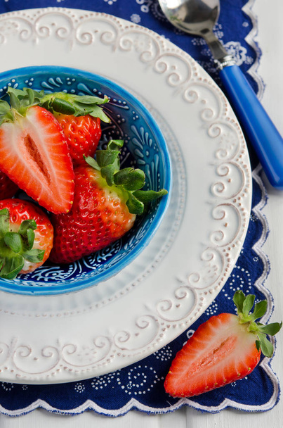 Fresas frescas en tazón sobre fondo azul brillante
 - Foto, Imagen