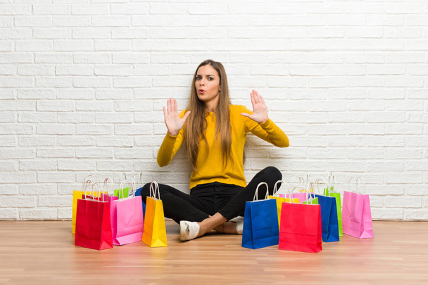 Young girl with lot of shopping bags making stop gesture with both hands - Фото, изображение