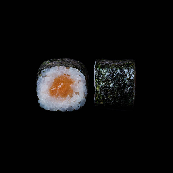 Sushi. Rolki z łososia w nori liść na białym tle w czarnym tle - Zdjęcie, obraz