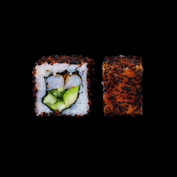 寿司。巻き揚げ鍋エビ、キュウリ、アボガド、トビコで分離されて黒の背景 - 写真・画像