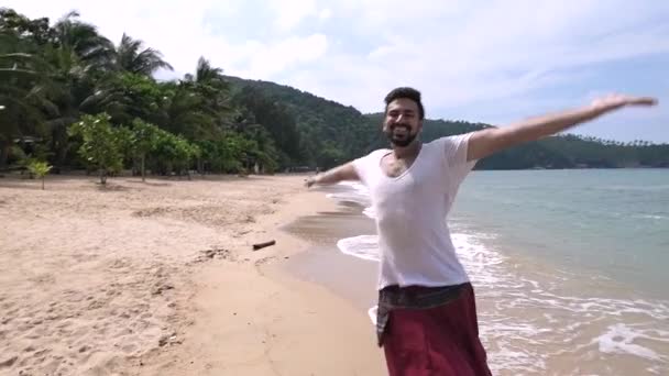 Um jovem e bonito homem corre ao longo da praia numa ilha tropical.
. - Filmagem, Vídeo