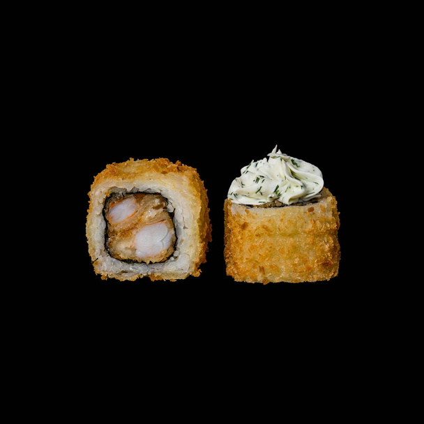 Σούσι. Ψημένο ρολό με γαρίδες τεμπούρα, τυρί κρέμα και βότανα, απομονώνονται σε μαύρο φόντο - Φωτογραφία, εικόνα
