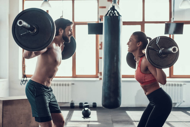 Man And Woman Are Lifting Barbells. Training Day. Fitness Club. Healthy Lifestyle. Powerful Athlete. Active Holidays. Crossfit Concept. Bright Gym. Working Out Together. Sportive Couple. - Фото, изображение