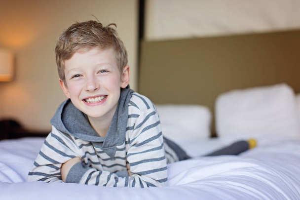 sonriente guapo caucásico chico disfrutando su día en hotel habitación
 - Foto, Imagen