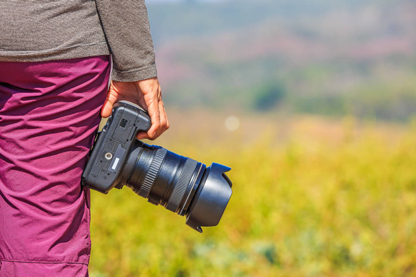 Photographer holds her DSLR camera in her right hand - Photo, Image