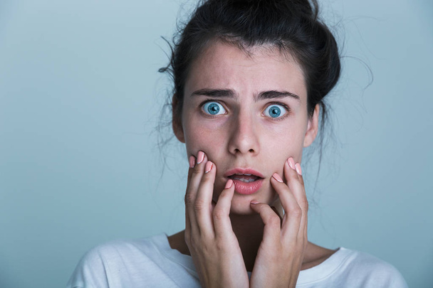 Close up of a shocked young woman wearing t-shirt isolated over blue background - Фото, зображення