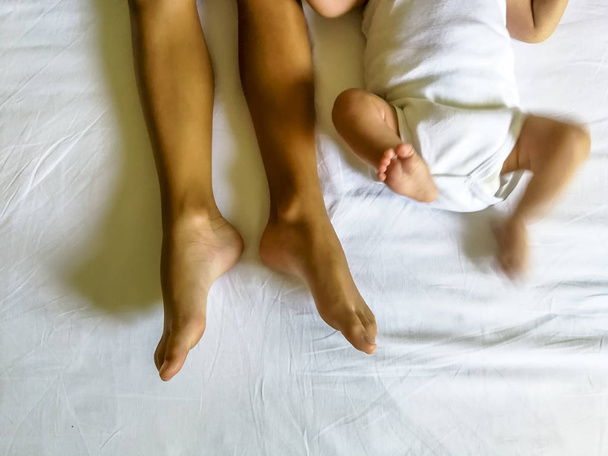 Pernas e pés de dois irmãos deitados na cama
 - Foto, Imagem