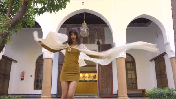 Piękne marokańskie dziewczyna przędzenia i machając jej biały płaszcz w malowniczej Dar Si powiedział Riyad w Marrakeszu na zachód słońca - Materiał filmowy, wideo