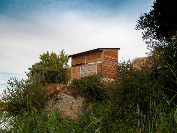 Uma casa de madeira gazebo em uma floresta em um dia nublado para observar pássaros
 - Foto, Imagem