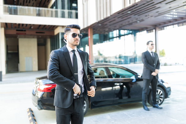 Trustworthy bodyguard removing handgun to protect boss in car on street - Photo, Image