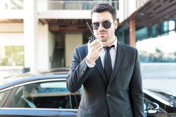 Eleganckie secret service agent za pomocą walkie-talkie, aby uniknąć niebezpieczeństwa dla bogatym biznesmenem w samochodzie - Zdjęcie, obraz