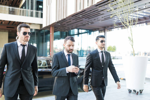 Personal bodyguards in suits protecting president while walking at campus - Valokuva, kuva