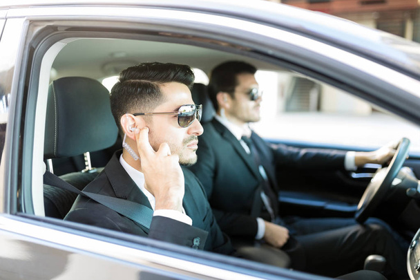 Bodyguard listening to safety instructions while sitting in car - Фото, зображення