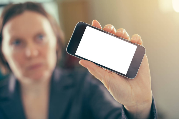 Businesswoman holding smartphone with blank mock up screen in the office, selective focus - Foto, immagini