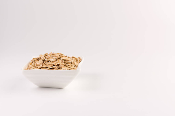 Dry rolled oatmeal in bowl isolated on white background. - Foto, immagini