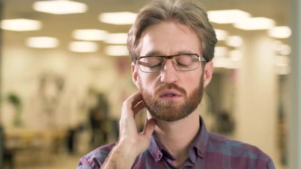Portrait of young attractive serious bearded guy in glasses and casual plaid shirt preoccupied with a difficult problem. - Video