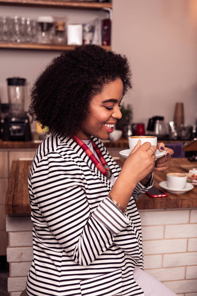 Joyeux belle femme regardant sa tasse avec cappuccino
 - Photo, image