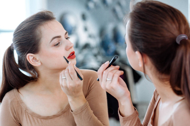 Beautiful woman looking mirror scratching her eyebrows. - Foto, imagen