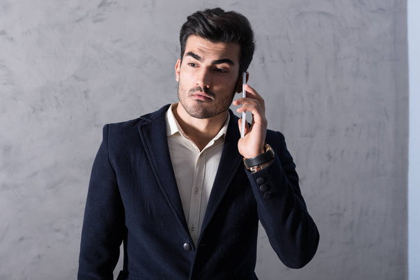 A serious young businessman talking on his phone in a suit - Foto, immagini