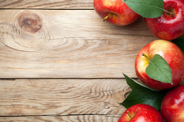 Punaiset omenat vihreät lehdet puinen pöytä. Kopioi tilaa. Yläkuva
 - Valokuva, kuva