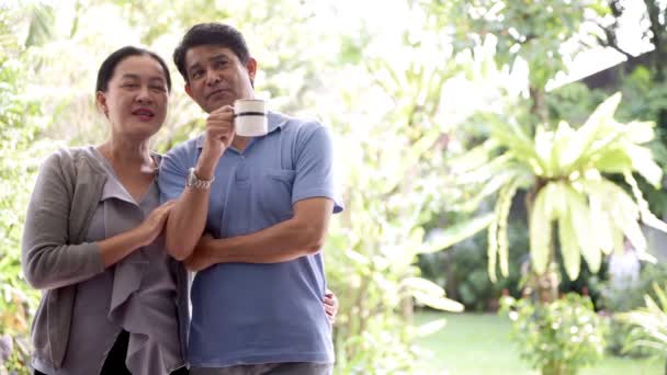 Senior Aziatische couple permanent voor camera met prachtige tuin op achtergrond, genieten van het moment. Senior levensstijl concept. - Video