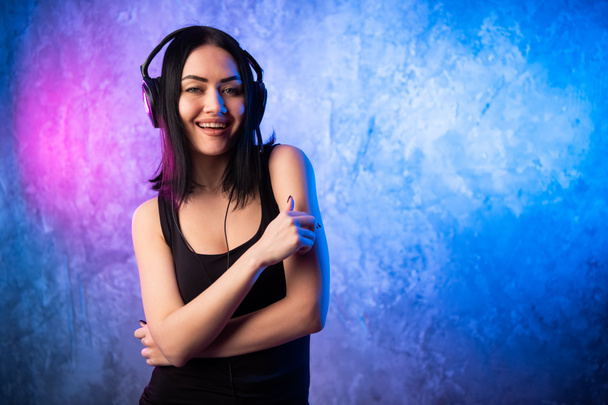 Portrait coloré en ligthe bleu et rose d'une jeune DJ femme portant un casque et profitant d'une musique électronique. - Photo, image