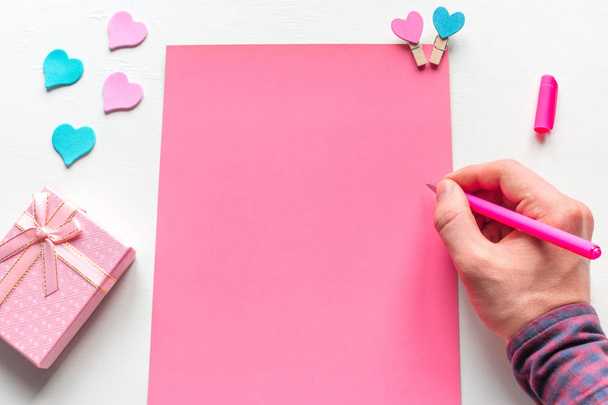 a man writes a congratulatory letter to a gift for Valentine's Day - Zdjęcie, obraz