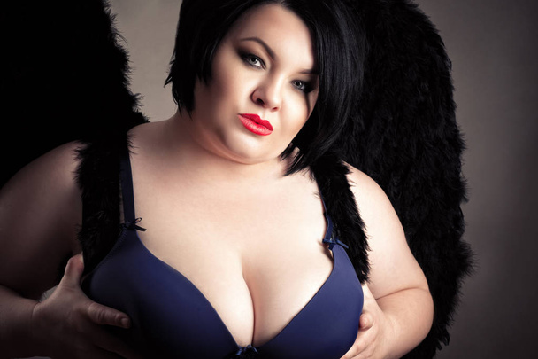 σέξι λίπος γυναίκα με μεγάλα στήθη στο σουτιέν με μαύρα φτερά  - Φωτογραφία, εικόνα