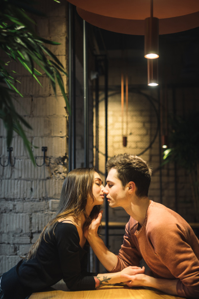 Theme love and holiday Valentines Day. couple of college students together in Caucasian heterosexual lovers winter inside the cafe sit at empty table embrace. Emotion happiness and love. - Foto, imagen