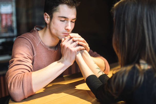 Theme love and holiday Valentines Day. couple of college students together in Caucasian heterosexual lovers winter inside the cafe sit at empty table embrace. Emotion happiness and love. - Photo, Image