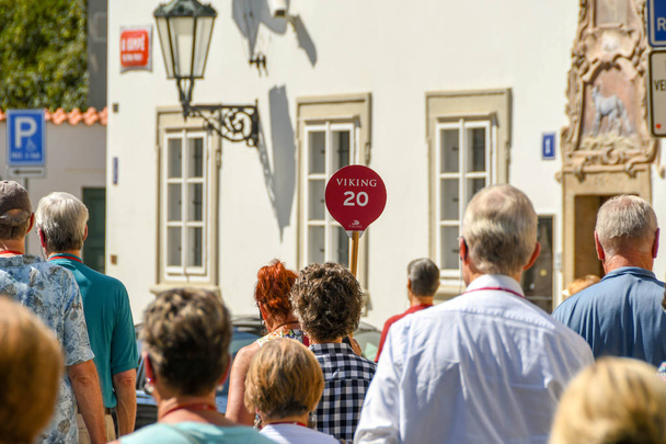 PRAGUE, REPÚBLICA CHECA - AGOSTO 2018: Pessoas que visitam Praga seguindo um guia turístico que está segurando uma bandeira vermelha
. - Foto, Imagem