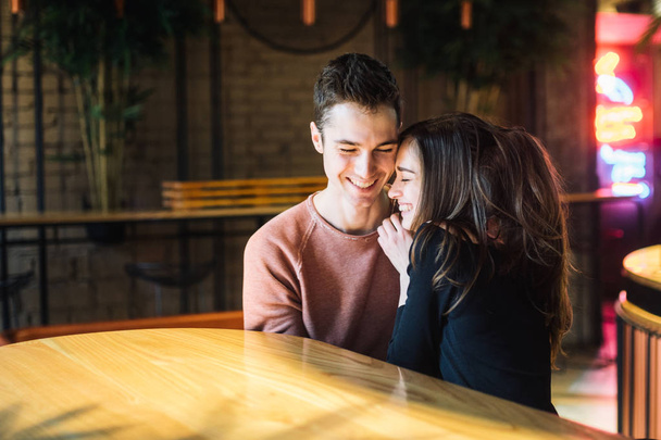 Theme love and holiday Valentines Day. couple of college students together in Caucasian heterosexual lovers winter inside the cafe sit at empty table embrace. Emotion happiness and love. - Foto, Imagen