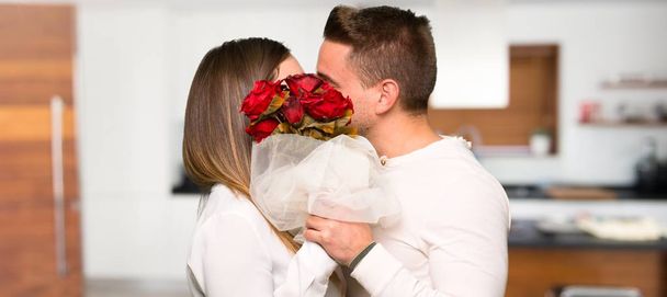 Couple in valentine day with flowers and kissing in a house - Fotografie, Obrázek