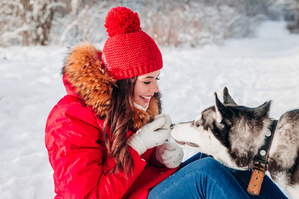 Young woman playing with her Husky dog in winter park - Φωτογραφία, εικόνα