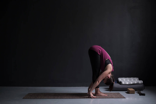 Mujer deportiva practicando yoga, de pie hacia adelante dobla ejercicio, uttanasana pose
. - Foto, imagen