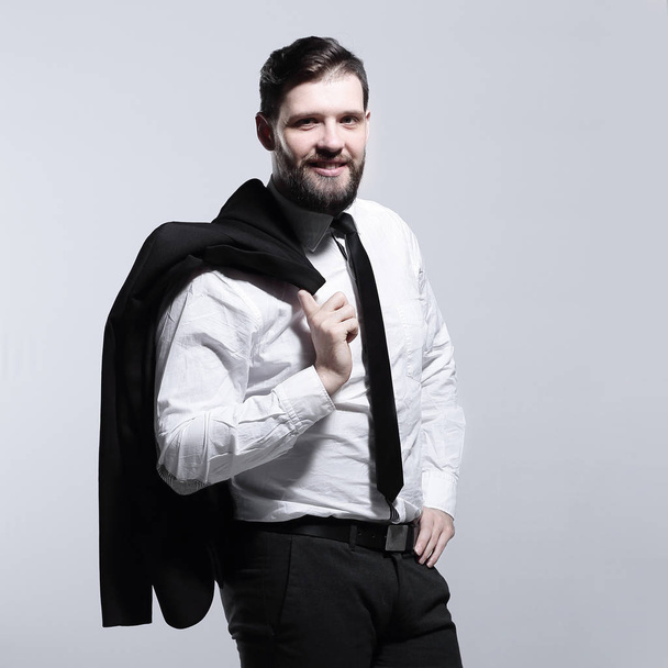 smiling businessman holding a jacket over his shoulder and straightens the tie - Fotoğraf, Görsel