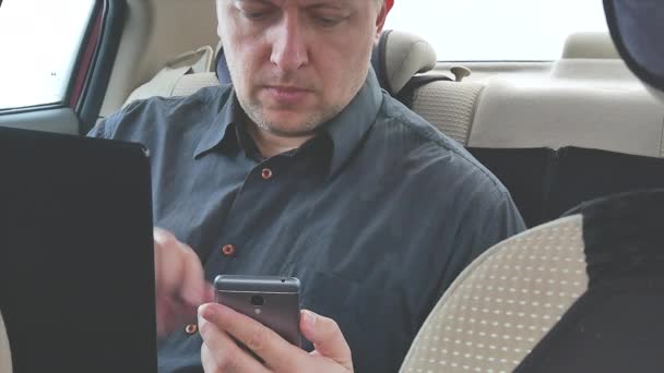 man at backseat of taxi car with laptop and smartphone making call. close-up 4k video footage - Filmmaterial, Video