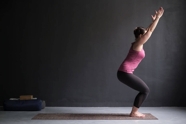 Frau praktiziert Yoga, Stuhlgymnastik, utkatasana Pose, Workout. - Foto, Bild