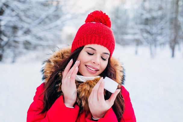 winter portrait of a beautiful woman with facial cream and snowflake on winter background. Face skin care in winter - Photo, Image