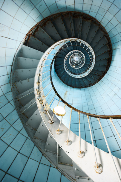 Спиральная лестница поднимается с голубой плиточной стеной
 - Фото, изображение