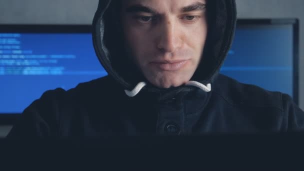 Bellissimo hacker maschio in cappuccio che lavora su un computer in una stanza buia dell'ufficio. Colpito su steadicam
 - Filmati, video