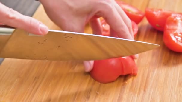 Close-up of female hands with a knife are cutting tomatoes for making salad on a wooden cutting board. Home kitchen. Healthy food - Footage, Video