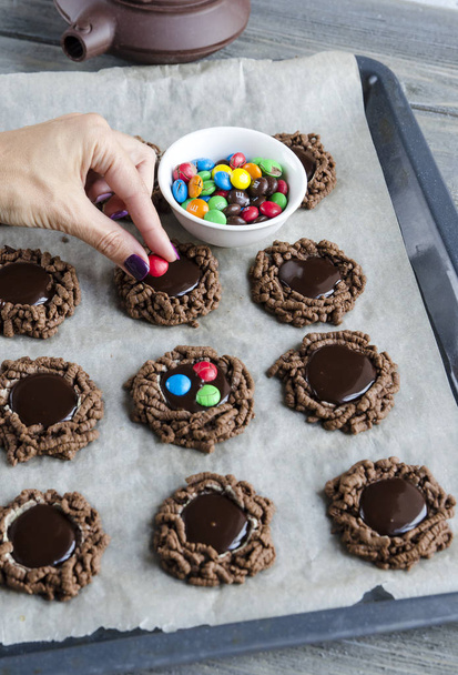 částečný pohled ženy zdobí dvojitá čokoláda čip cookies s barevné bonbóny - Fotografie, Obrázek