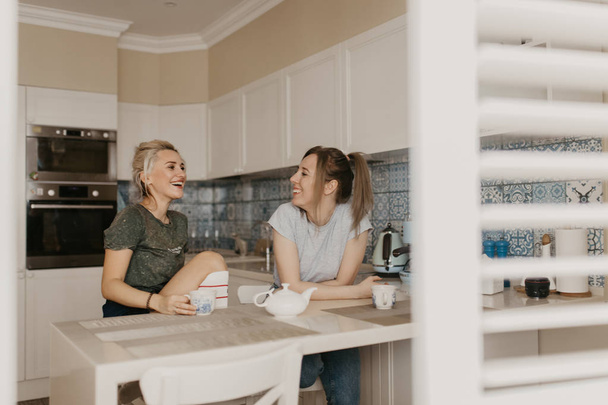Zwei Freunde trinken Tee in der Küche, lachen und unterhalten sich. authentische Emotion - Foto, Bild