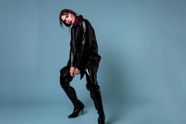 Fashion short hair model with colorful makeup in black leather jacket leather knee-high boots - 写真・画像