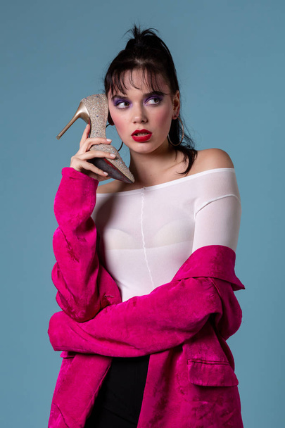 De jonge vrouw mode met kleurrijke make-up met behulp van een hoge hak schoen als een telefoon - Foto, afbeelding