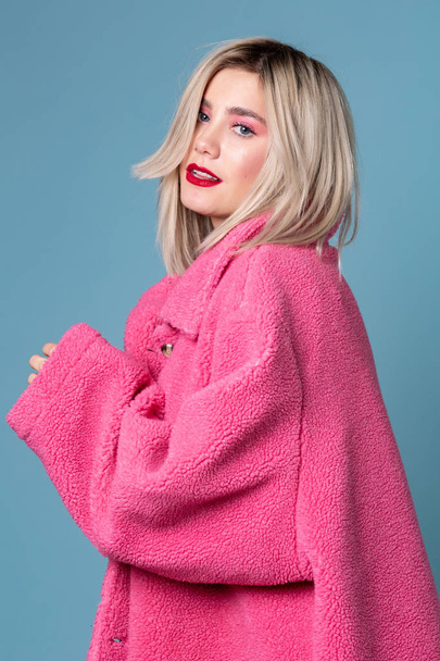 Beautiful blonde fashion model seductively posing in pink coat - Photo, Image