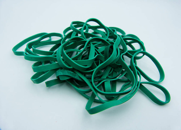 Montón de bandas de goma verdes colocadas sobre una mesa blanca
 - Foto, Imagen