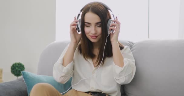 Woman listening a music at home in big headphones - Кадри, відео