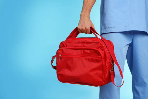 Male doctor with first aid kit and space for text on color background, closeup. Medical object - Foto, Imagen